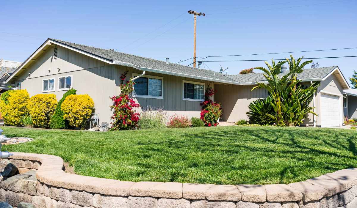 Modest, residential home in the Bay Area. Green lawn in front, blue sky above.